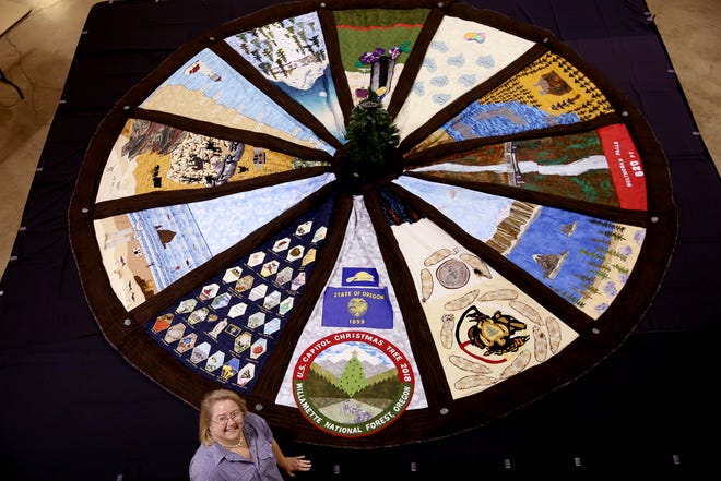 Elizabeth Hill stands near a 14-foot tree skirt created for the 2018 U.S. Capitol Christmas Tree, which will come from the Willamette National Forest in Oregon. The tree skirt, created by the Gone to Pieces Quilt Guild out of Yamhill County, features panels with scenes from around Oregon and will be on display at the Oregon State Fair from Aug. 24 - Sept. 3. Photographed at the Oregon State Fairgrounds in Salem on Thursday, Aug. 23, 2018.
