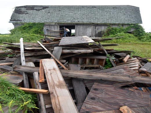 Barn artist Catie Newell of Detroit climbs scaffolding as she prepares to work on her barn-art project. Much of this wood from the barn's hayloft will be repurposed.