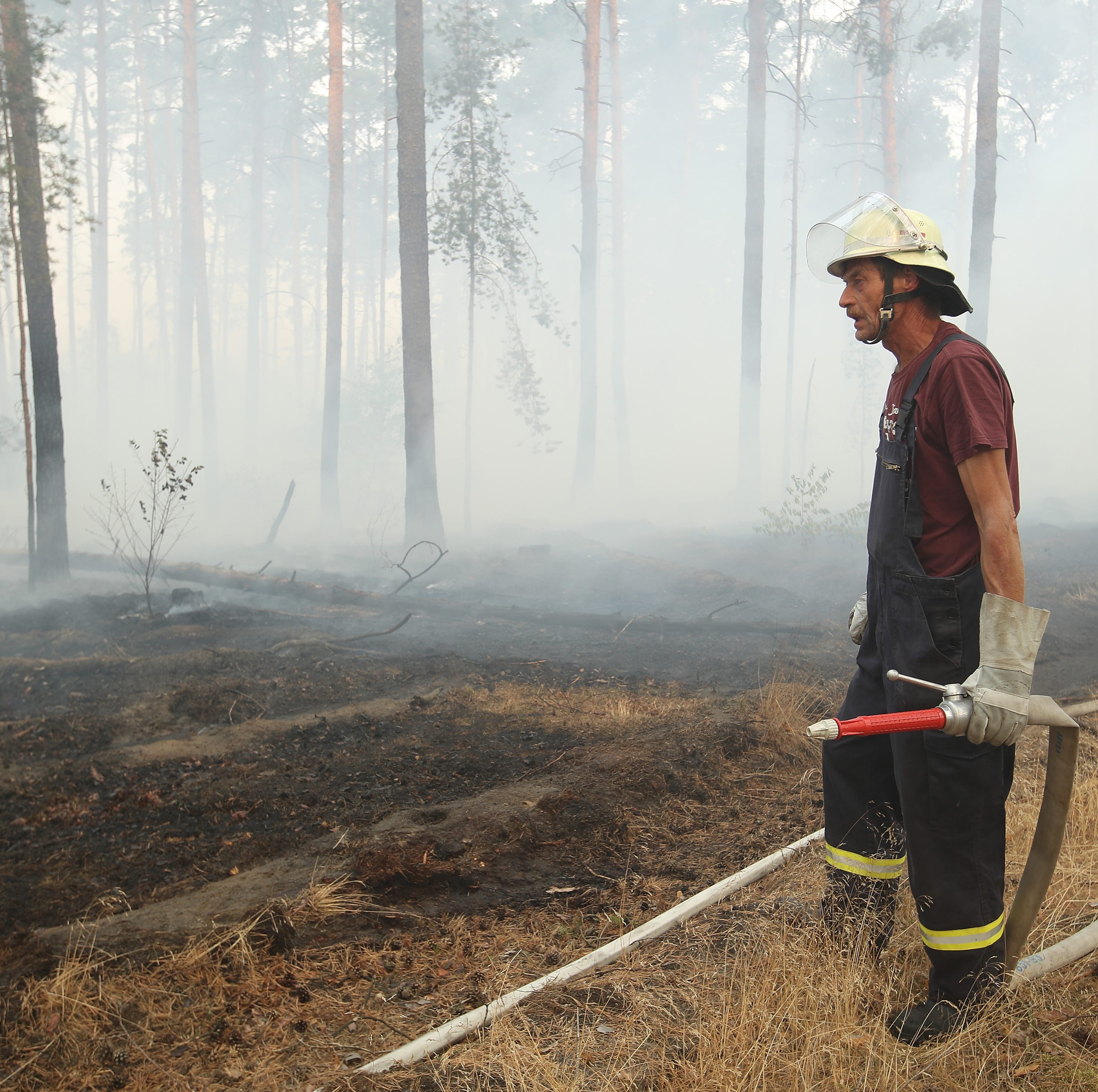 A fireman stands among smoke in a section of burning forest in southern Brandenburg state on August 24, 2018 near Klausdorf, Germany.