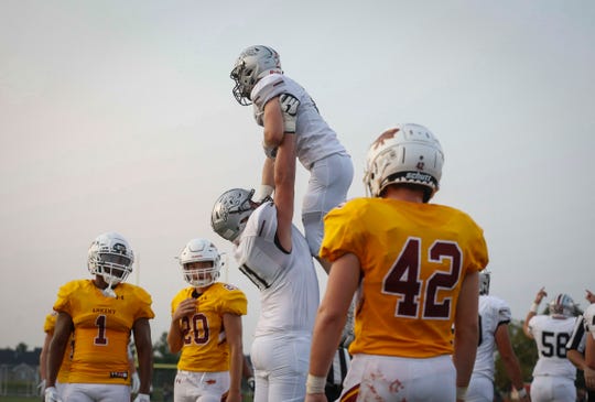 Ankeny Centennial junior running back Avery Gates is lifted up by teammate Brady Petersen after running in for a touchdown against Ankeny at Ankeny Stadium on Friday, Aug. 24, 2018.