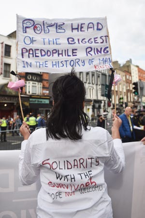 A protester holds up a sign in reference to the sex abuse scandal within the Catholic Church as Pope Francis travels through the city in the Popemobile on Aug. 25, 2018, in Dublin, Ireland.
