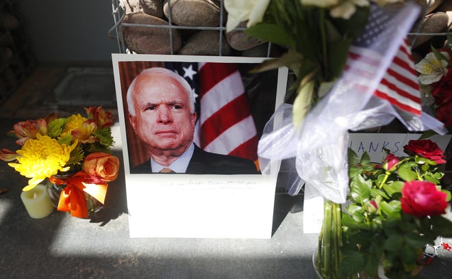 Flowers, flags and portraits of the late Sen. John McCain sit Aug. 26, 2018, outside McCain's offices at a memorial in Phoenix.