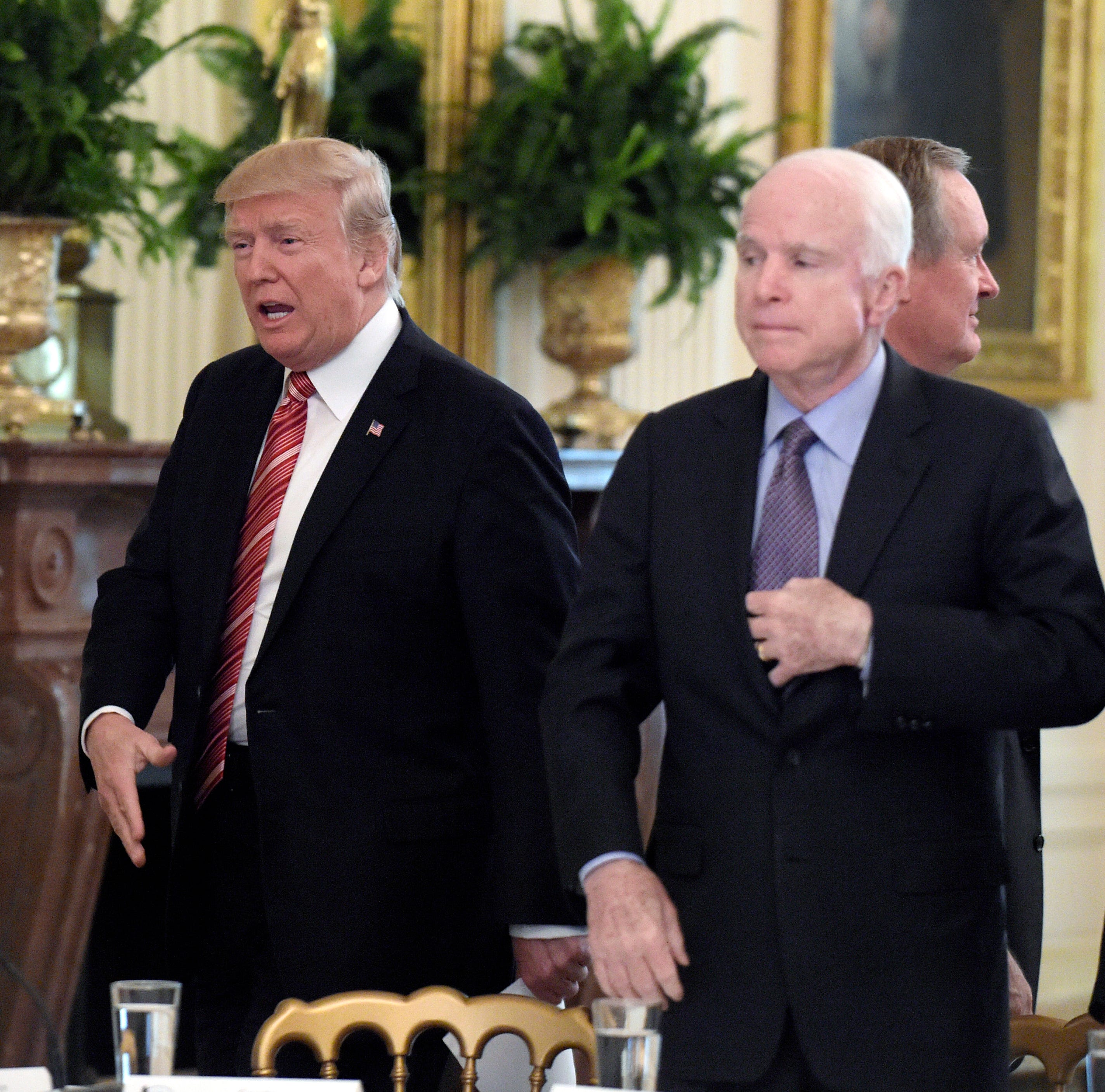 President Donald Trump reached out to shake hands with Sen. Todd Young, R-Ind., as he arrived for a meeting with Republican senators on health care in the East Room of the White House on June 27, 2017. Sen. John McCain, R-Ariz., who later cast the de