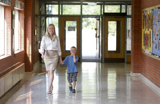 Lewis and Clark Elementary School Principal Jackie Mainwaring walks James Bonifay, a kindergartner, to class on the first day of school.