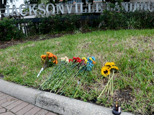 Flowers and a candle are left at the The Jacksonville Landing complex on Aug. 28, 2018, in Jacksonville, Fla. The complex reopened to the public Tuesday after three people were killed Sunday, including the gunman, at a video game tournament. 