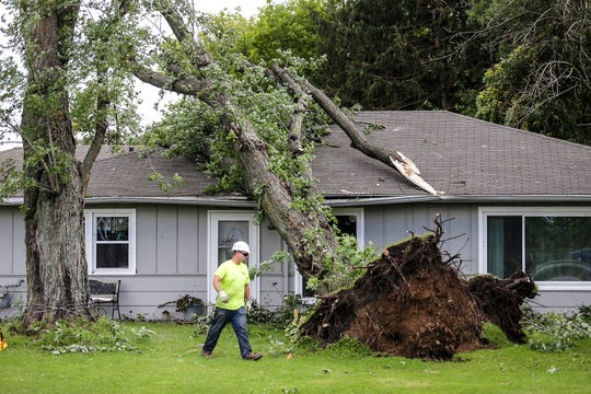Tony Voigt of K&B Tree and Lawn Care makes his way around a tree on a house Wednesday at N3041 South Frontage Road near Waupun. Severe weather Tuesday afternoon raked across the Waupun area causing widespread damage.