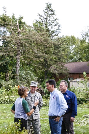 Jo Ann Gouin talks about damage her house sustained during the tornadoes with, from left, Donald Dunbar of the Wisconsin National Guard, Wisconsin Governor Scott Walker and Brian Satura of Wisconsin Emergency Management Thursday in the backyard of her Highland Street house in Brownsville.