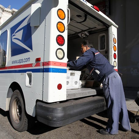 SAN FRANCISCO, CA - DECEMBER 05:  US Postal Service letter carrier Juan Padilla arranges mail in his truck while on his delivery route on December 5, 2011 in San Francisco, California. The US Postal Service announced today that they are considering a plan to eliminate the first class next-day delivery for stamped letters as well as closing half of its 487 mail processing plants across the country in an effort to cut costs and avoid bankruptcy.  (Photo   by Justin Sullivan/Getty Images)