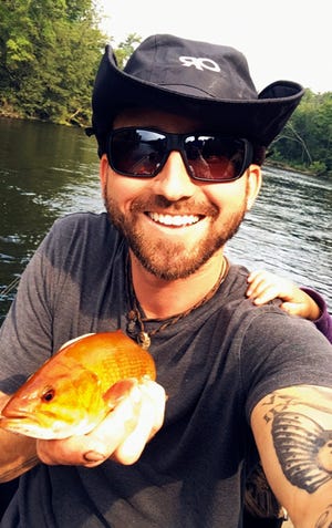 This Aug. 25, 2018, photo provided by Paul Gillis shows Gillis holding a rare orange fish he caught during a fishing trip on the Muskegon River in Michigan. Gillis said he first thought he'd caught a goldfish. But a Department of Natural Resources Fisheries wildlife biologist identified the fish on Wednesday, Aug. 29 as a rarely-spotted, orange-colored smallmouth bass.