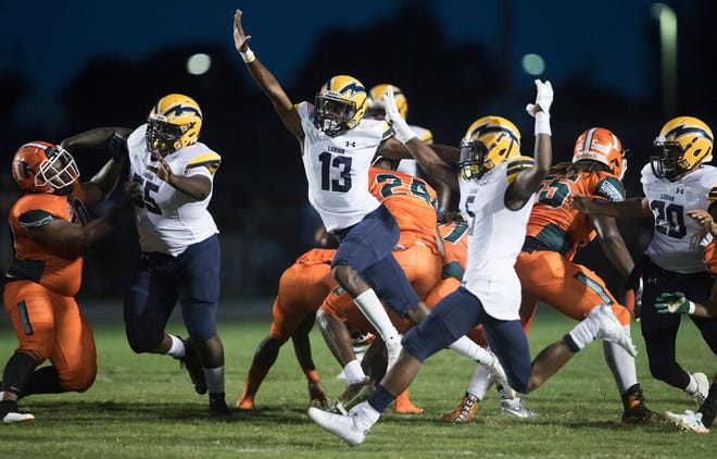 Lehigh High School’s Omarion Cooper (13), center, blocks a Dunbar extra point on Thursday at Dunbar in Fort Myers. Lehigh beat Dunbar 12-6.