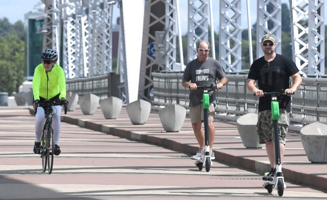 People ride Lime electric scooters on the John Seigenthaler Pedestrian Bridge on Aug. 31, 2018.