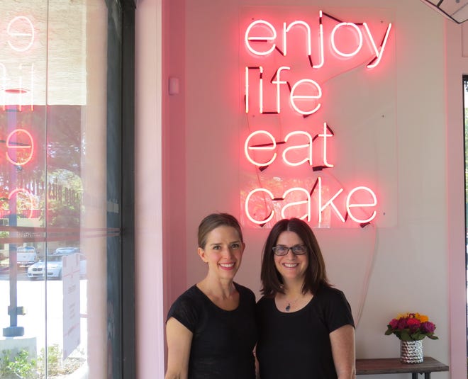 Pastry chef Elizabeth Belkind, left, and former TV and film producer Lisa Olin pose in the Westlake Village location of Cake Monkey, the bakery they launched more than a decade ago in Los Angeles. Both sites include neon signs that read "Enjoy Life Eat Cake."