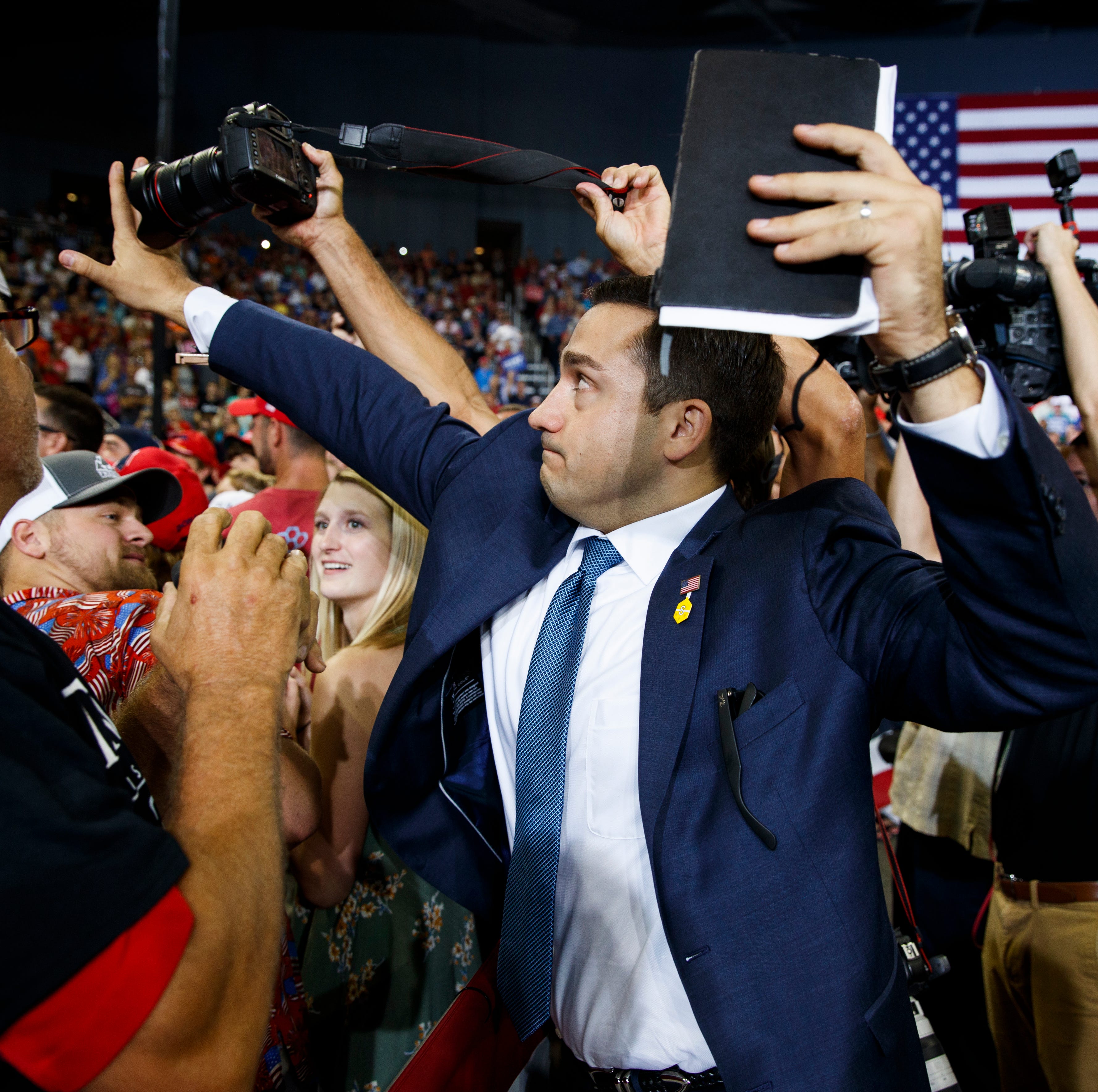 A staff member for President Donald Trump blocks a camera as a photojournalist attempts to take a photo of a protester during a campaign rally at the Ford Center, Thursday, Aug. 30, 2018, in Evansville, Ind.