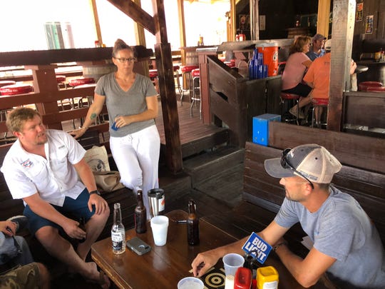 Connor Masterson, left, Meaghan Enright, and Jeff Quinlan, who run non-profit foundations for St. John recovery, plan upcoming projects at a bar in Cruz Bay.