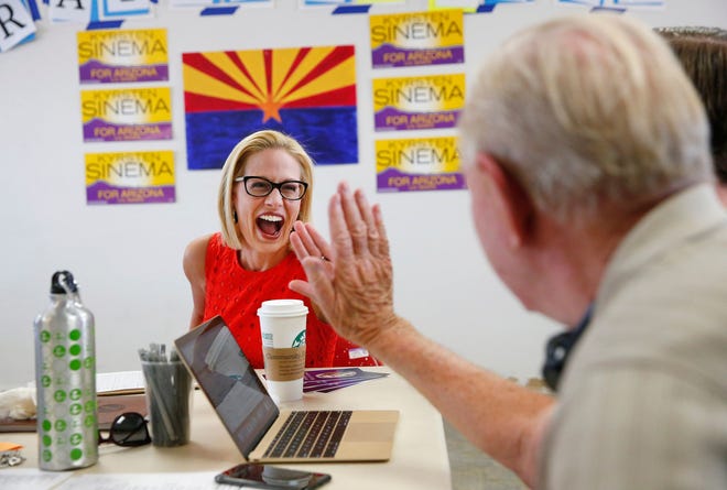 Will Democratic U.S. Rep. Kyrsten Sinema be part of the 'blue wave?' She high-fives volunteer Bob Miller at her Phoenix field office on Aug. 28, 2018.
