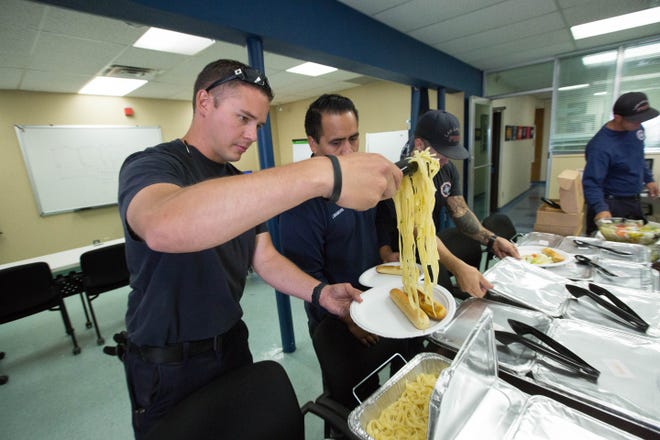 Camron Clark, Las Cruces firefighter at Fire Station 1, serves himself a helping of spaghetti from the trays of food donated by Olive Garden to LCFD and Las Cruces Police on Labor Day , Monday Sept. 3, 2018.