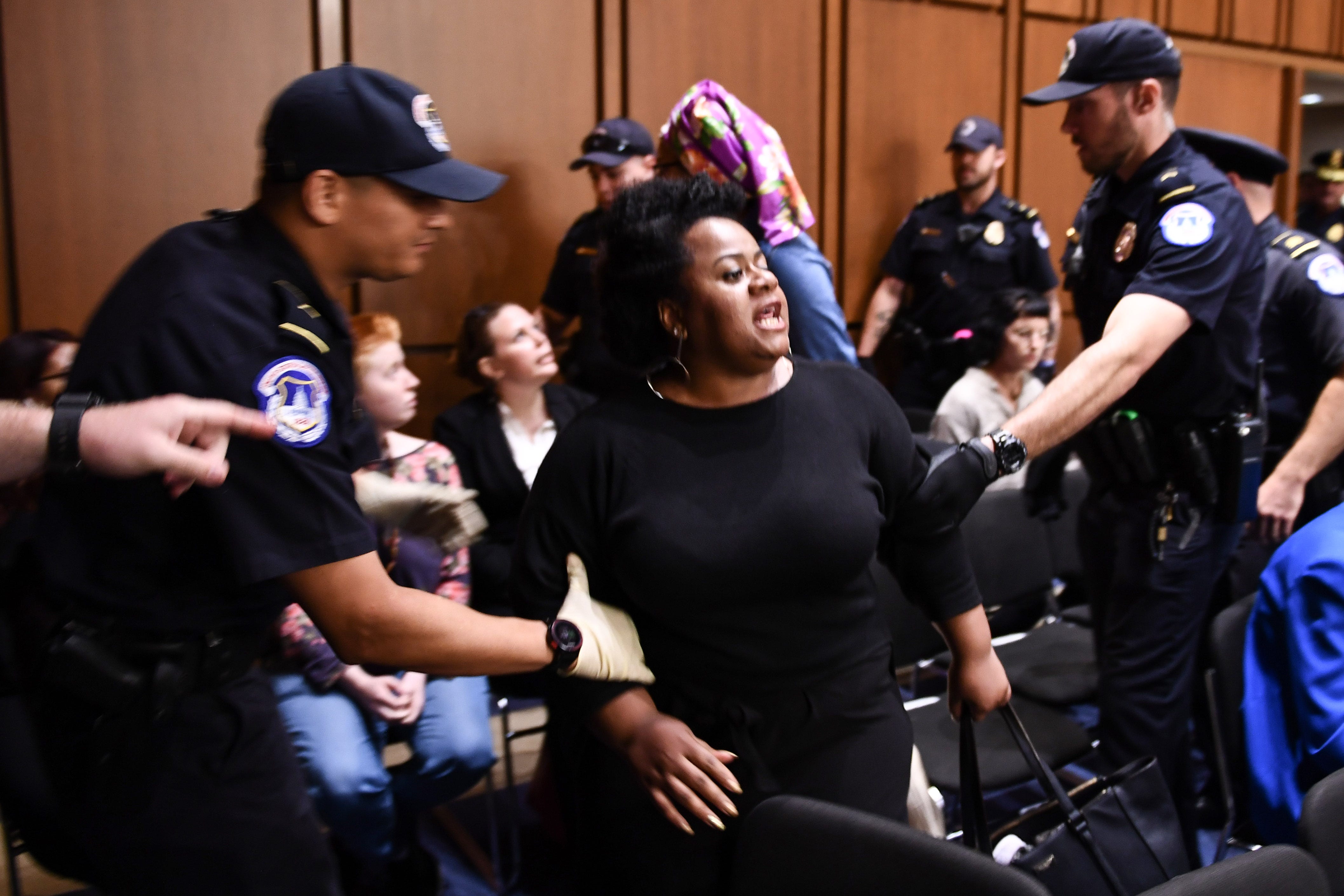 A protestor is escorted out of the room as US Supreme Court nominee Brett Kavanaugh  attends the first day of his confirmation hearing in front of the US Senate on Capitol Hill in Washington DC, on September 4, 2018. - President Donald Trump's newest Supreme Court nominee Brett Kavanaugh is expected to face punishing questioning from Democrats this week over his endorsement of presidential immunity and his opposition to abortion. Some two dozen witnesses are lined up to argue for and against confirming Kavanaugh, who could swing the nine-member high court decidedly in conservatives' favor for years to come. Democrats have mobilized heavily to prevent his approval. (Photo by Brendan Smialowski / AFP)BRENDAN SMIALOWSKI/AFP/Getty Images ORIG FILE ID: AFP_18U51Z