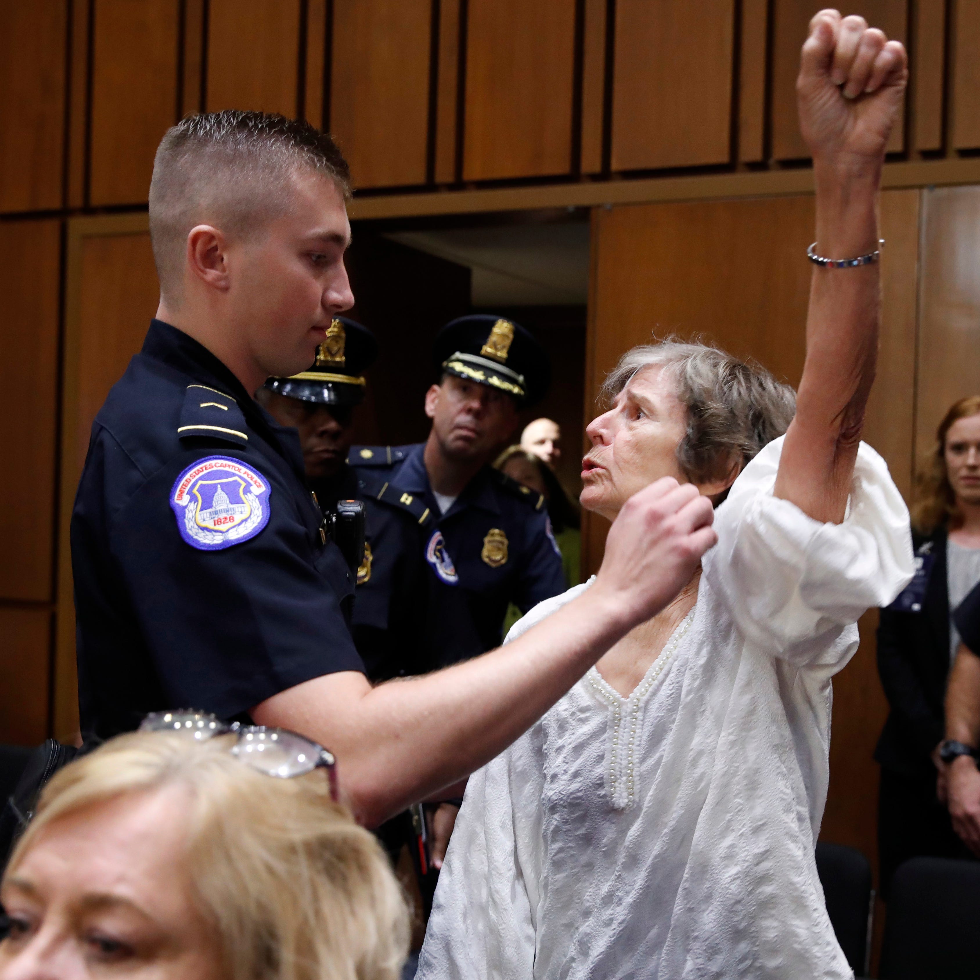 A woman stands and voices her opposition to Supreme Court nominee Brett Kavanaugh, during a Senate Judiciary Committee confirmation hearing on his nomination for Supreme Court, on Capitol Hill, Tuesday, Sept. 4, 2018, in Washington.  (AP Photo/Jacque