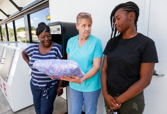 Dee Lawson, center, presents a memory pillow to Slyolandra Patterson's mother Linda Carter, left, and sister Desiree Fillmore, right. Patterson was found dead with a gunshot wound on Saturday, Aug. 25, 2018 inside a home in the 2600 block of South Fremont Avenue.