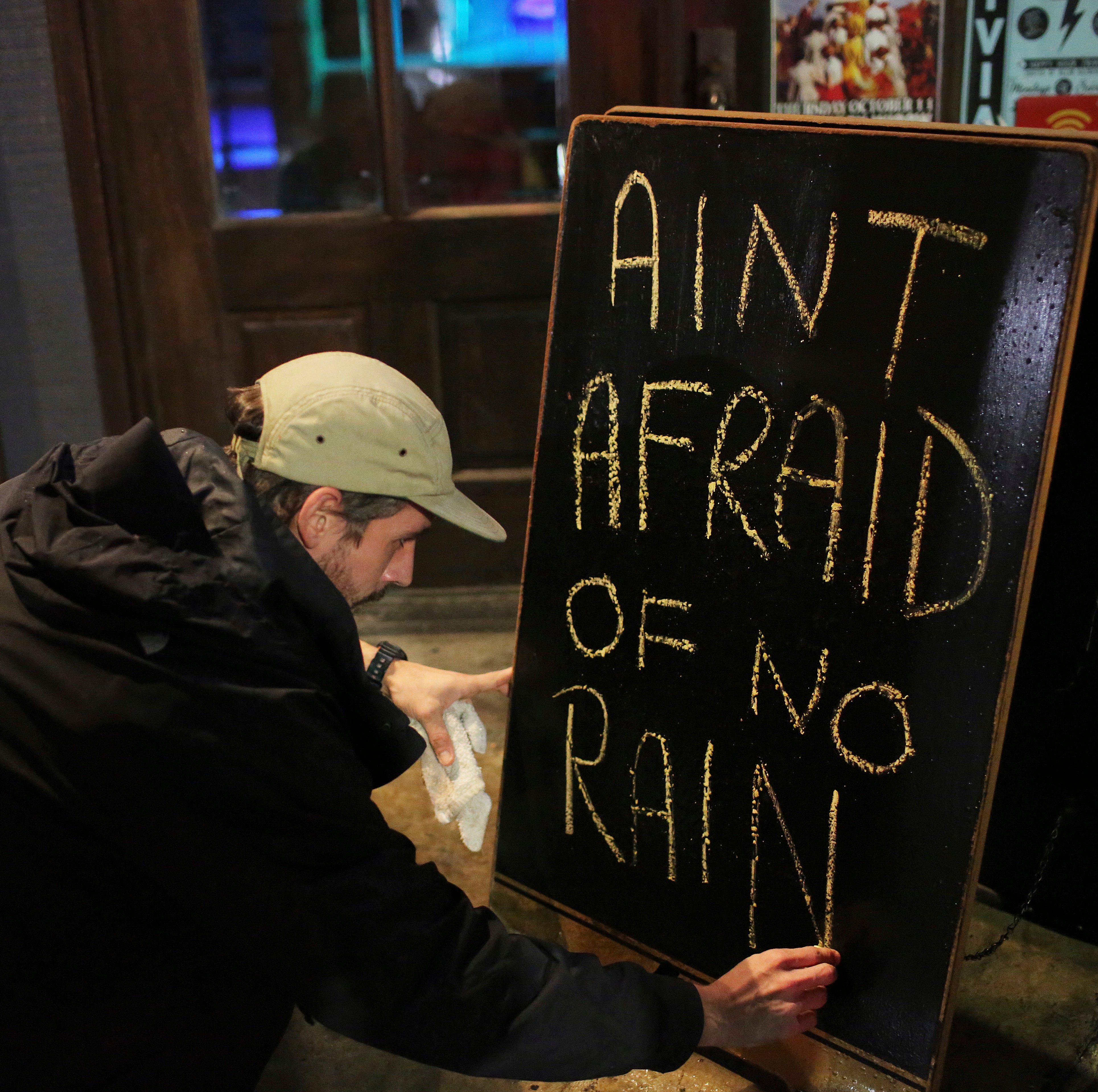 Nick Eberlein, bartender at The Merry Widow, draws a new sign as Tropical Storm Gordon arrives at night on Tuesday, Sept. 4, 2018 in Mobile, Ala. Tropical-force winds from fast-moving Gordon smashed into the coastline of Alabama and the western Flori