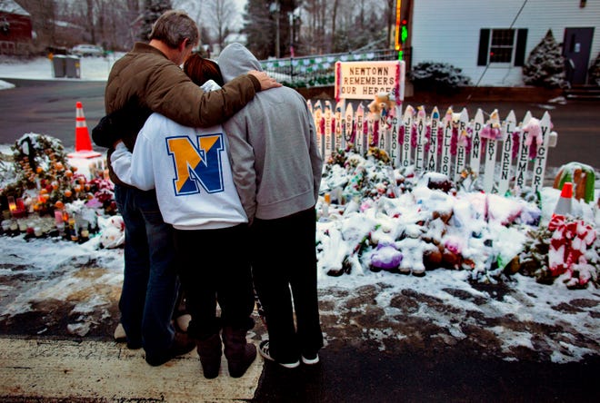 Members of the Rutter family of Sandy Hook, Conn., embrace early Christmas morning as they stand near memorials by the Sandy Hook firehouse in Newtown, Conn.,Tuesday, Dec. 25, 2012. People continue to visit memorials after gunman Adam Lanza walked into Sandy Hook Elementary School in Newtown, Conn., Dec. 14, and opened fire, killing 26, including 20 children, before killing himself.  (AP Photo/Craig Ruttle)