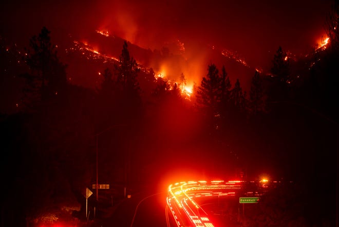 Fire trucks pass the Delta Fire burning in the Shasta-Trinity National Forest, Calif., Sept. 5, 2018. Parked trucks lined more than two miles of Interstate 5 as both directions remained closed to traffic. 