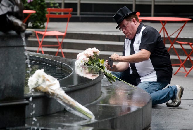 John Rabold takes a picture of flowers on Fountain Square on Friday, Sept. 7, 2018, in Downtown Cincinnati.  The square is was opened Friday morning after a gunman opened fire leaving four dead, including the shooter, and two injured. 