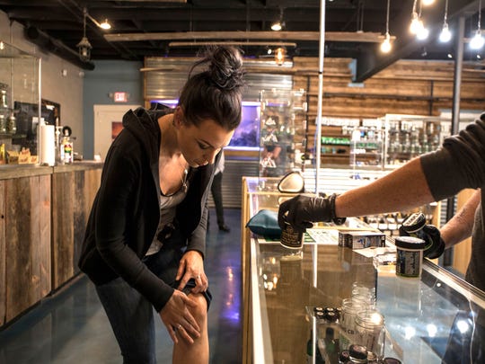 Meghan Martin, 31 of Lake Orion, applies CBD topical salve to a leg injury at The Reef medical marijuana dispensary in Detroit on Thursday, September 6, 2018.