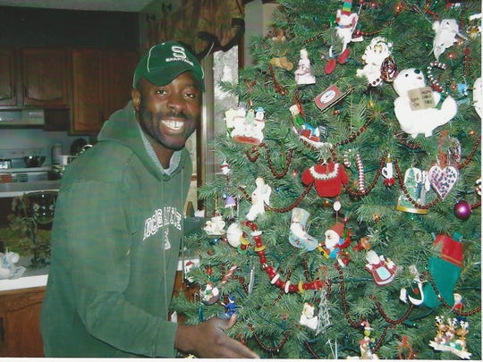Francis Anwana, 48, an immigrant from Nigeria, stands next to a Christmas tree, in Michigan. He's lived in the U.S. since he was 14, but now faces deportation.