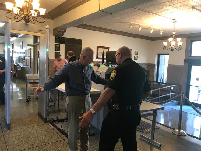 A man gets searched by an officer on the first floor of the Madison County Courthouse after passing through the new metal detector.