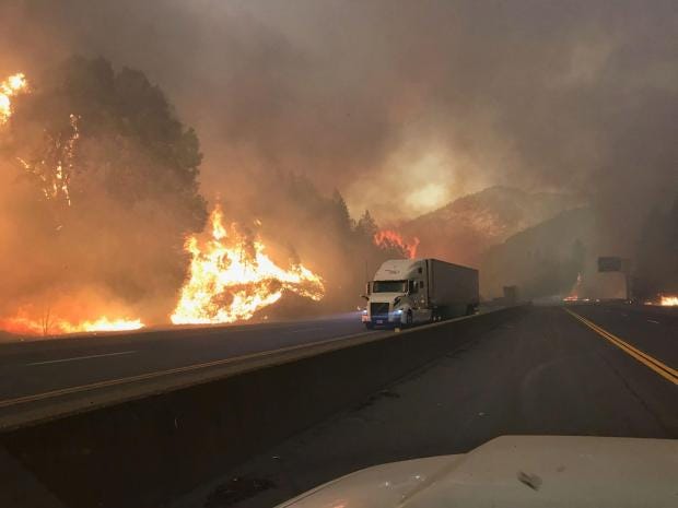 A big rig on Interstate 5 passes next a wall of flames from the Delta Fire on Sept. 5, 2018.