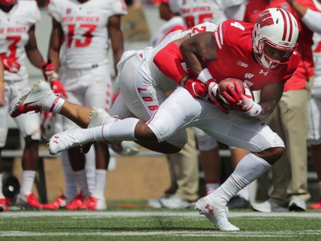 Wisconsin wide receiver A.J. Taylor holds on to the ball while being covered by New Mexico safety Marcus Hayes.