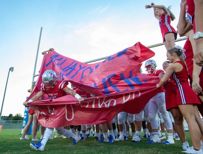 A Macon East football player bursts through a banner before kickoff against Fort Dale Academy.