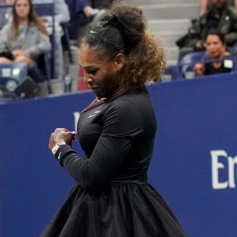 Serena Williams smashes her racket after losing a...