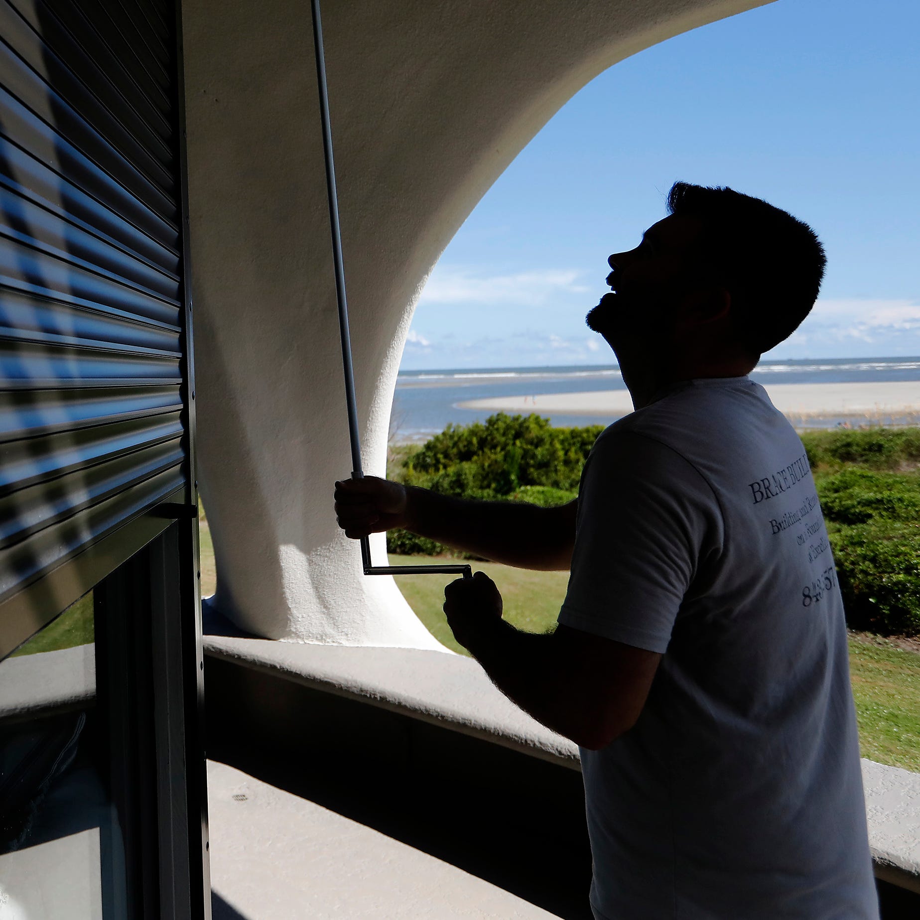 Chris Brace, from Charleston, S.C. lowers hurricane shutters on a client's house in preparation for Hurricane Florence at Sullivan's Island, S.C., Monday, Sept. 10, 2018. Brace said that after S.C. Gov. Henry McMaster ordered an evacuation the proper