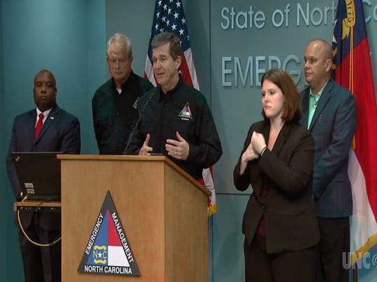 Flanked by N.C. Director of Emergency Management Mike Sprayberry to his immediate left, other state officials and a sign language interpreter, Gov. Roy Cooper describes expected impacts from Hurricane Florence during a press conference Tuesday in Raleigh in this image taken from a UNC-TV livestream of the event.
