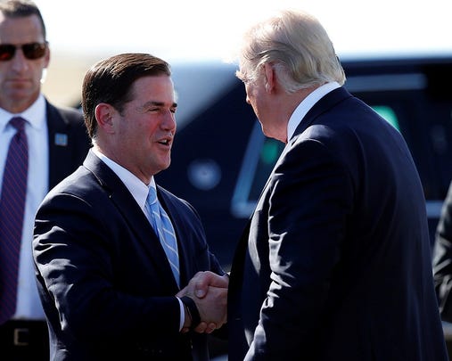 President Donald Trump greets Arizona Gov. Doug Ducey (left) after stepping off Air Force One as he arrives on Aug. 22, 2017, in Phoenix.