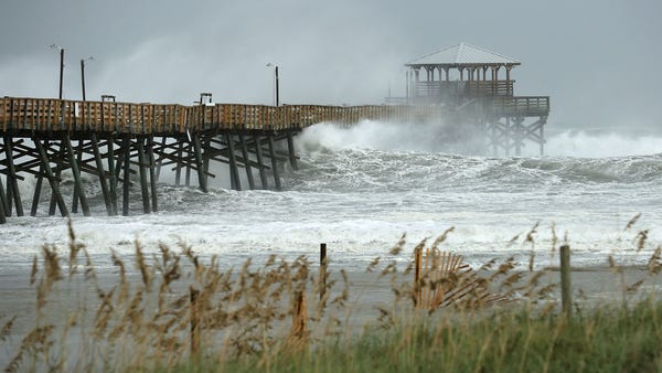 Waves crash around the Oceana Pier as the outer...