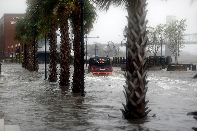 People drive an ATV through floodwaters on the riverwalk in Wilmington, N.C., after Hurricane Florence made landfall Friday, Sept. 14, 2018.