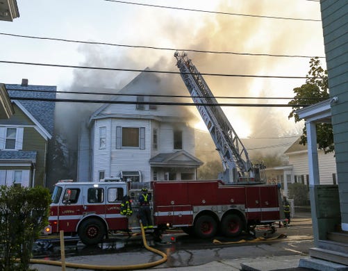 Firefighters battle a fire in a house in Lawrence, Mass.