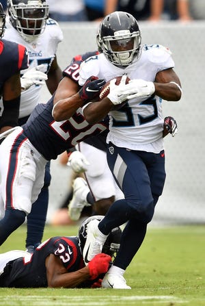Titans running back Dion Lewis (33) gets wrapped up by Texans safety Justin Reid (20) and cornerback Johnson Bademosi (23) in the second half Sunday.