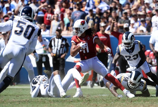 Cardinals receiver Larry Fitzgerald runs with the ball during the first half of a game against he Rams.