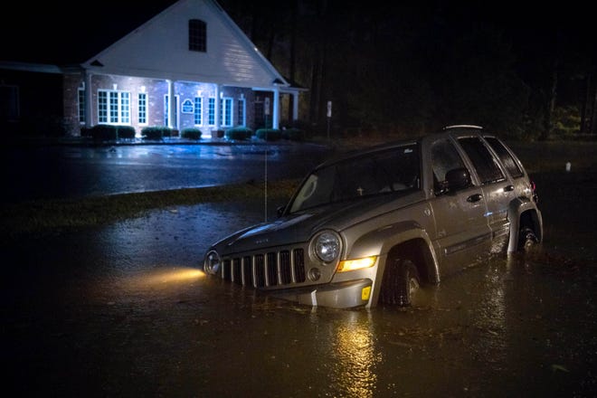 An abandoned SUV sits in a flooded neighborhood as rain from tropical storm Florence continues to fall on Lumberton, N.C., on Sept. 15, 2018.