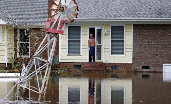 A man peers from his flooded home in Lumberton, N.C., Sunday, Sept. 16, 2018, in the aftermath of Hurricane Florence.