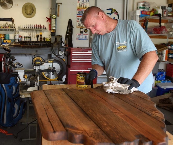 Mark Brown of Ohio Made Rustic stains an Ohio table top while working in his garage. Brown's first commissioned piece was for his wife and he has since expanded the business.