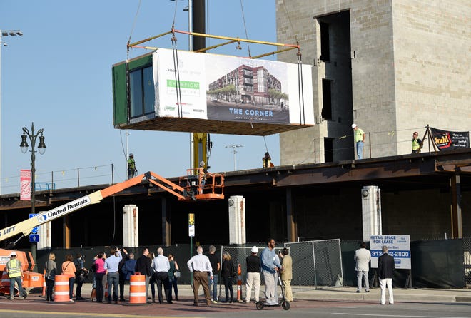 A crowd watches as a modular unit is installed at "The Corner," a $30 million mixed-use development project at the corner of Michigan and Trumbull, on Tuesday.