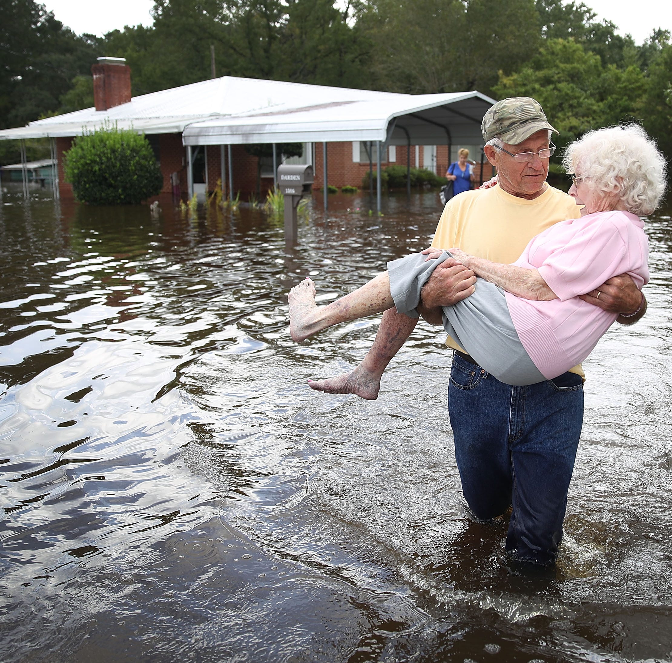 Bob Richling carries Iris Darden as water from the Little River starts to seep into her home on Sept. 17, 2018 in Spring Lake, North Carolina. Flood waters from the cresting rivers inundated the area after the passing of Hurricane Florence.