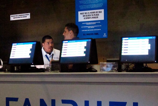 This July 14, 2018 photo, workers at the FanDuel sports book at the Meadowlands Racetrack in East Rutherford N.J. prepare to take bets moments before opening.   New Jersey gambling regulators are investigating whether FanDuel should be ordered to pay a New Jersey man $82,000 for a bet he made on a football game at what the company said were erroneously high odds. (AP Photo/Wayne Parry)