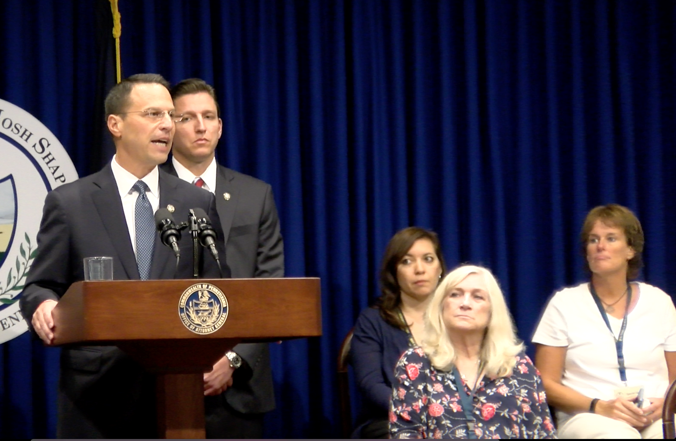 Diana Vojtasek and Mary McHale sit behind Judy Deaven on stage during a grand jury presentment by Pennsylvania Attorney General Josh Shapiro in Harrisburg on Aug. 14. Vojtasek and McHale are survivors of abuse by the same priest, James Gaffney.