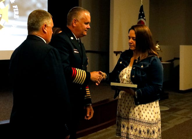 Jennifer Patterson, right, shakes hands with Ohio Fire Marshall Jeff Hussey as she accepts an award honoring her husband Joe Patterson Thursday, Sept. 20, 2019, at the state fire marshal's office in Reynoldsburg. Joe Patterson died June 24 from injuries he received while working with compressed air cylinders at Paint Creek Joint Fire District.
